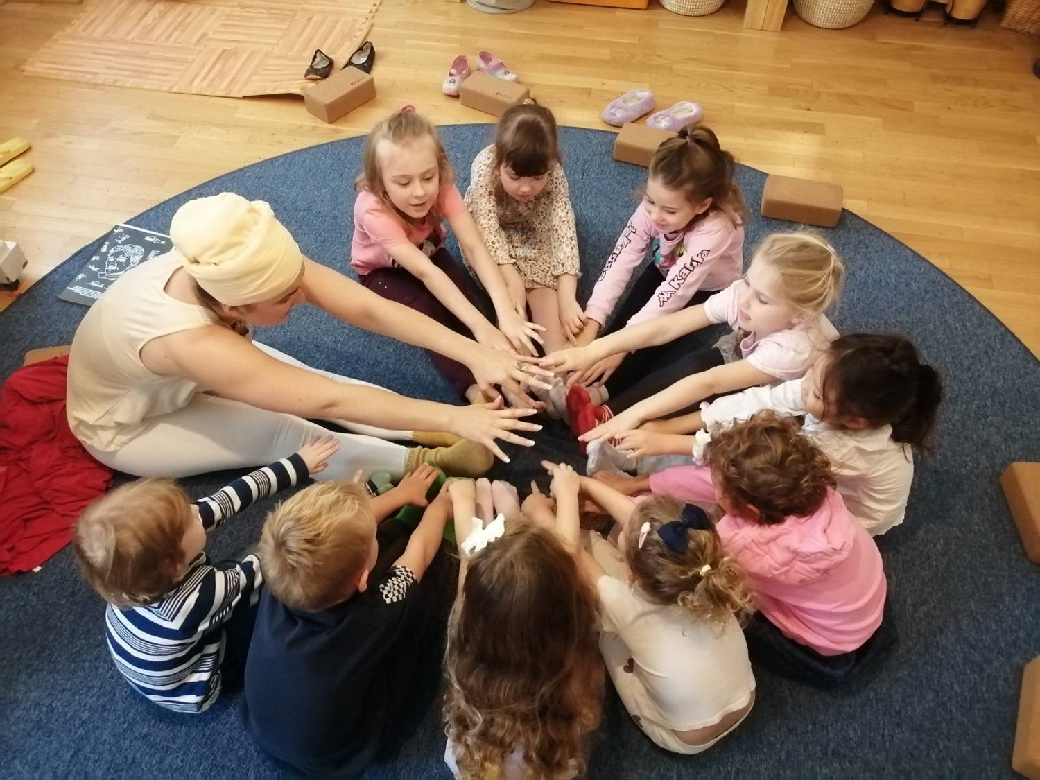 Kinder und eine Erwachsene legen im Kreis ihre Hände zusammen